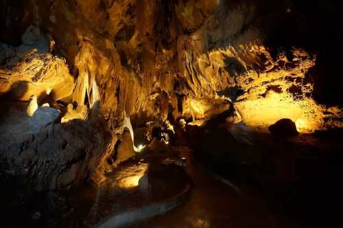 A dimly lit cave with dramatic rock formations and warm lighting illuminating the walls.