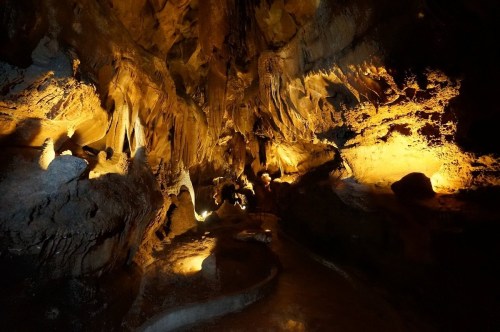 A dimly lit cave with dramatic rock formations and warm lighting illuminating the walls.