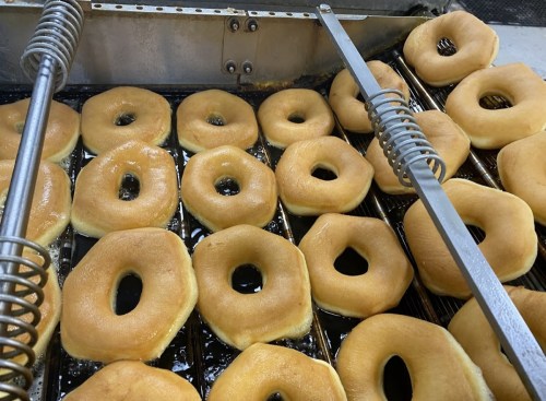 Freshly fried donuts cooling on a rack, golden brown with a classic ring shape.