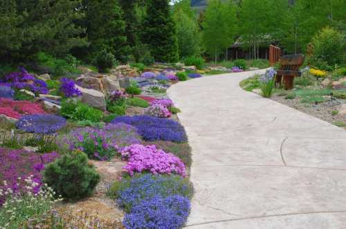 A winding path through a vibrant garden filled with colorful flowers and lush greenery.