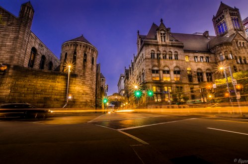 Historic buildings at dusk with light trails from passing cars and a vibrant sky.