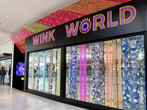 Colorful storefront display for "Wink World" featuring vibrant patterns and reflective elements.