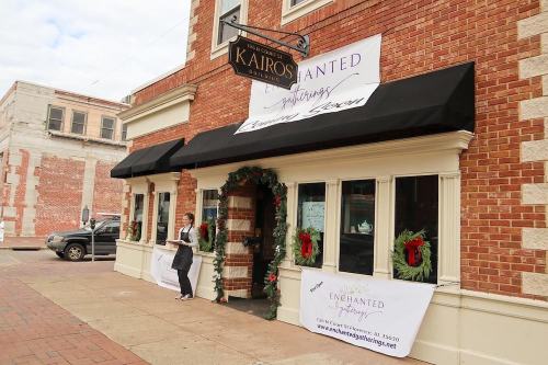 A storefront with holiday decorations and a sign announcing "Enchanted Gatherings" coming soon.