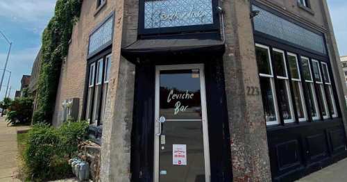 Exterior of a bar with a black facade and large windows, featuring a sign that reads "Ceviche Bar."