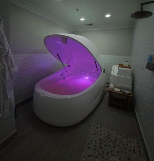 A modern floatation tank with purple lighting in a serene bathroom setting. Soft lighting and a cozy atmosphere.