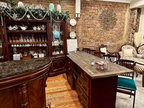 Cozy café interior featuring a wooden counter, brick wall, and elegant seating with decorative elements.