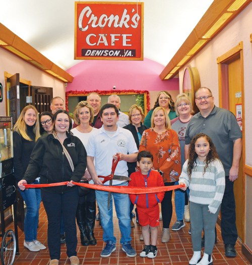 A group of people gathers at Cronk's Cafe for a ribbon-cutting ceremony, celebrating the cafe's opening in Denison, VA.