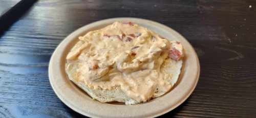 A plate with a thick, creamy spread on a piece of bread, featuring bits of meat or vegetables.