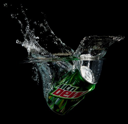 A can of Mountain Dew splashes into water, creating a dynamic burst of droplets against a black background.