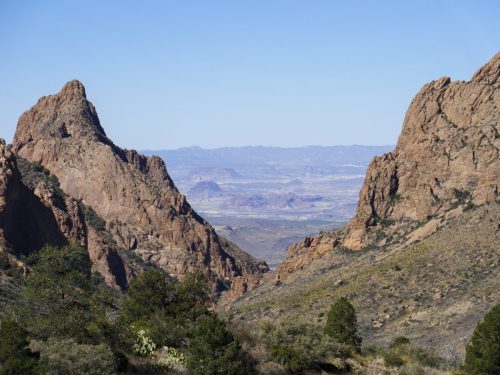 A scenic view of rugged mountains and a valley under a clear blue sky.