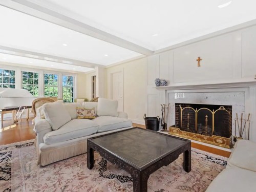 Bright living room featuring a cozy sofa, coffee table, fireplace, and large windows with natural light.