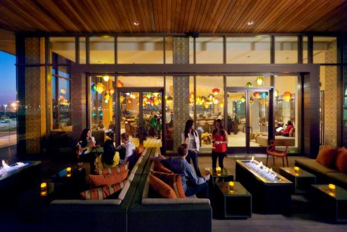 A stylish lounge with colorful lanterns, cozy seating, and people socializing in a warm, inviting atmosphere.