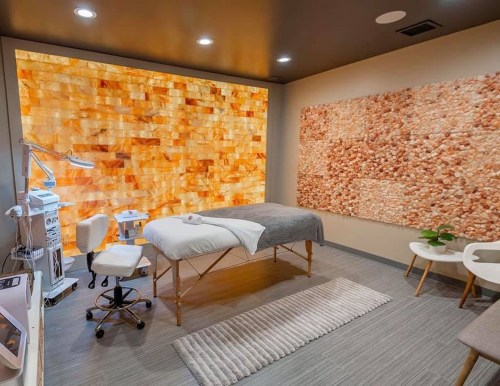 A serene spa room featuring a salt wall, massage table, and calming decor for relaxation and wellness treatments.