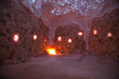 A serene salt cave with textured stone walls, glowing salt crystals, and a soft, starry ceiling.