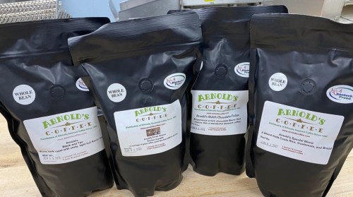 Four bags of Arnold's Coffee, labeled as whole bean, displayed on a countertop.