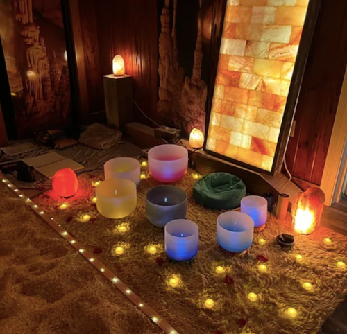 A serene space with glowing salt lamps, crystal bowls, and soft lighting, creating a calming atmosphere.