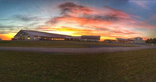 A panoramic view of buildings silhouetted against a vibrant sunset sky with colorful clouds.