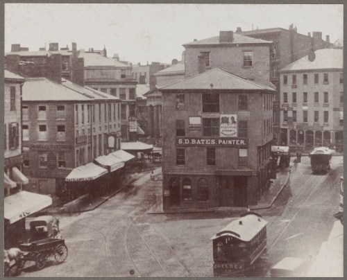 Historic black-and-white photo of a street scene featuring buildings, horse-drawn carriages, and a sign for S.D. Bates, Painter.