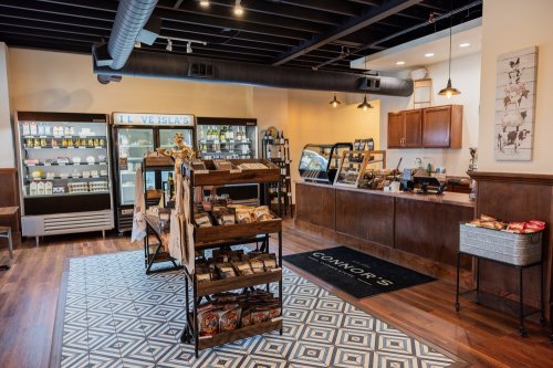 A cozy café interior featuring wooden shelves, a display case, and a welcoming counter with seating.