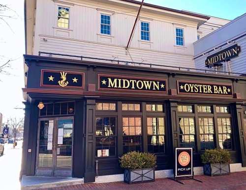 Exterior of Midtown Oyster Bar, featuring a black facade with gold lettering and a "Pick Up" sign in front.