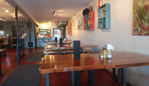 Interior of a restaurant featuring wooden tables, colorful wall art, and a cozy atmosphere.