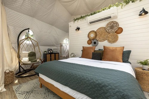Cozy bedroom with a green and white color scheme, featuring a bed, hanging chair, and decorative wall art.