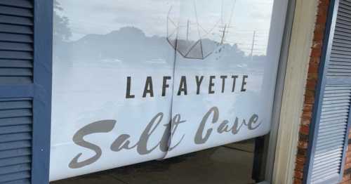 Sign for "Lafayette Salt Cave" displayed on a window, featuring a minimalist design and light colors.