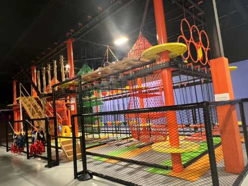 Indoor adventure playground featuring climbing structures, nets, and colorful obstacles. Safe, enclosed play area.