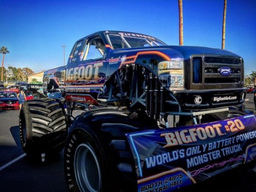 A large blue monster truck with "Bigfoot" branding, showcasing oversized tires and a vibrant design at an outdoor event.