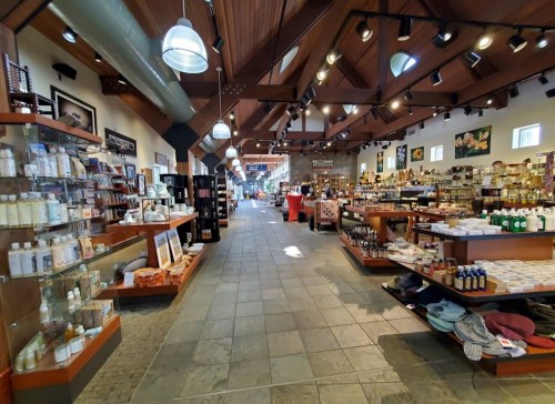 A spacious store interior with wooden beams, shelves of products, and bright lighting, creating a welcoming atmosphere.
