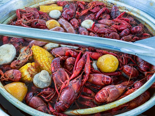 A pot filled with boiled crawfish, corn, potatoes, and spices, showcasing a vibrant mix of seafood and vegetables.