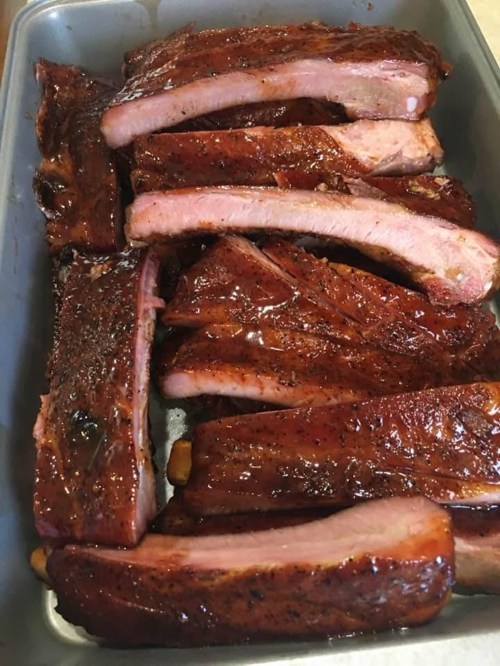 A tray of glazed, barbecued pork ribs arranged neatly, showcasing a rich, smoky color and tender meat.