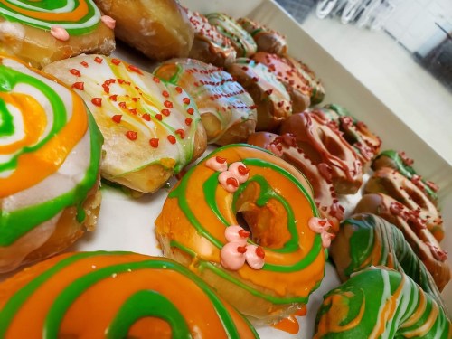 A variety of colorful donuts with vibrant icing and decorations arranged on a tray.