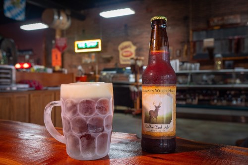 A frosty mug of beer next to a bottle labeled "Golden Bock Ale" in a rustic bar setting.