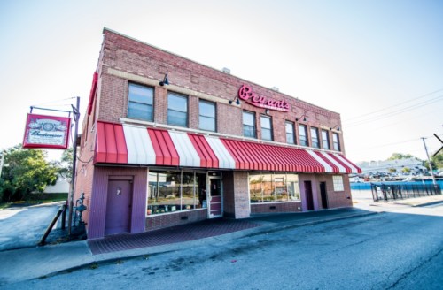 A brick building with red and white striped awning, featuring large windows and a sign that reads "Bryant's."
