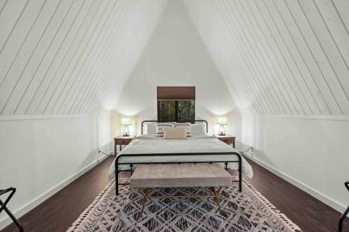 Cozy A-frame bedroom with a large bed, two lamps, and a decorative rug under a sloped ceiling.