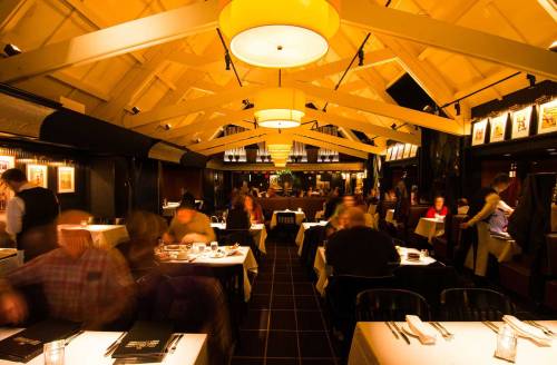 A bustling restaurant interior with warm lighting, tables set for dining, and patrons enjoying their meals.