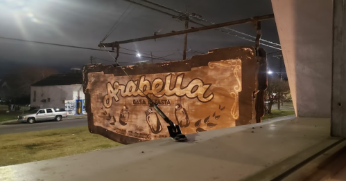 A wooden sign for "Arabella Casa de Pasta" hangs outside, illuminated by streetlights at night.
