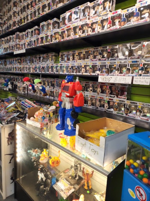 A colorful toy robot stands on a display counter, surrounded by shelves filled with collectible figures and various toys.
