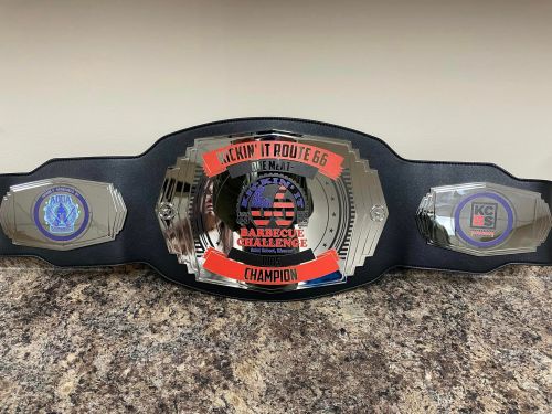 A shiny championship belt for the "Kickin' It Route 66 Barbecue Challenge," featuring logos on either side.