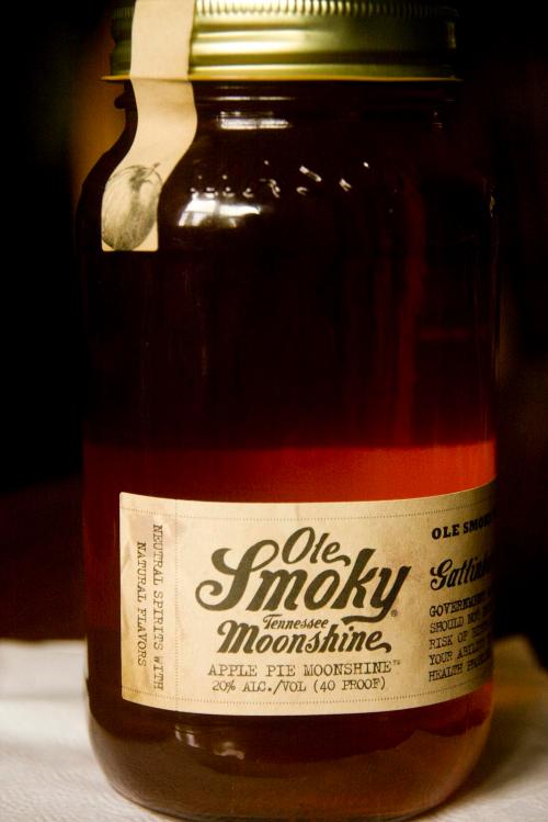 A jar of Ole Smoky Tennessee Moonshine labeled "Apple Pie Moonshine," 20% alcohol, with a rustic design.