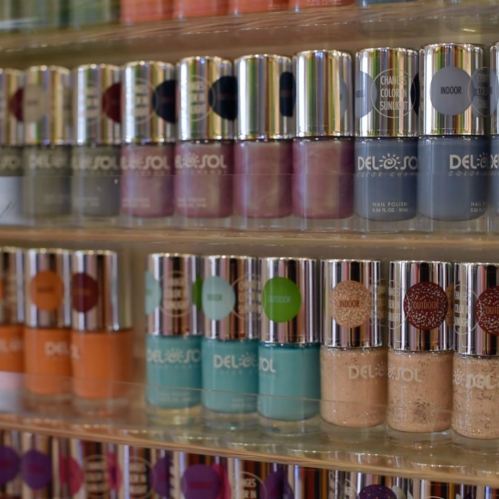 A display of colorful nail polish bottles arranged on a shelf, showcasing various shades and finishes.