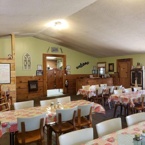 Cozy dining area with wooden tables, checkered tablecloths, and a welcoming sign on the wall.