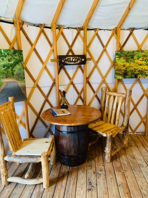 Cozy interior of a yurt featuring a wooden table, two chairs, and nature-themed wall art.