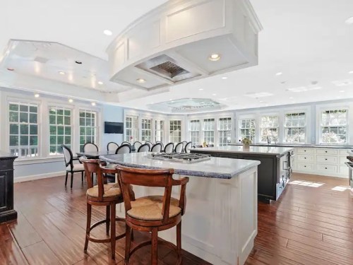 Spacious modern kitchen with a large island, bar seating, and abundant natural light from multiple windows.