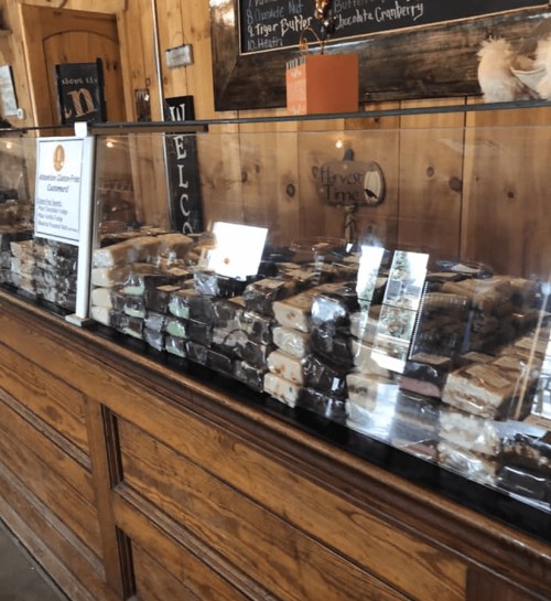 A display case filled with various types of fudge and treats in a wooden shop setting.