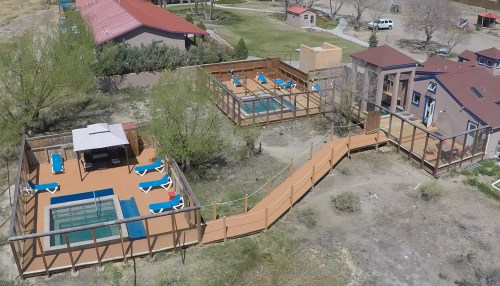 Aerial view of a property featuring two pools, wooden decks, and surrounding greenery.