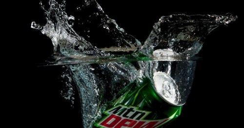 A can of Mountain Dew splashes into water, creating dynamic waves and bubbles against a black background.