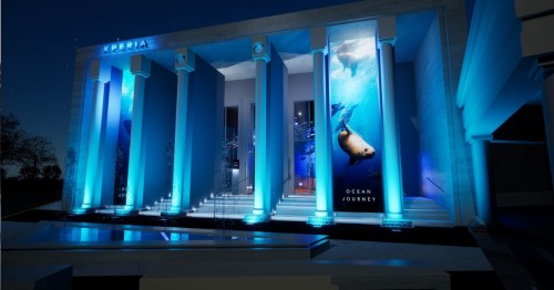 A modern building with blue lighting and ocean-themed murals, featuring columns and a serene nighttime atmosphere.