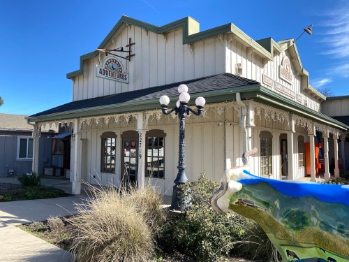 A charming building with a sign reading "Adventures," featuring decorative architecture and a clear blue sky.